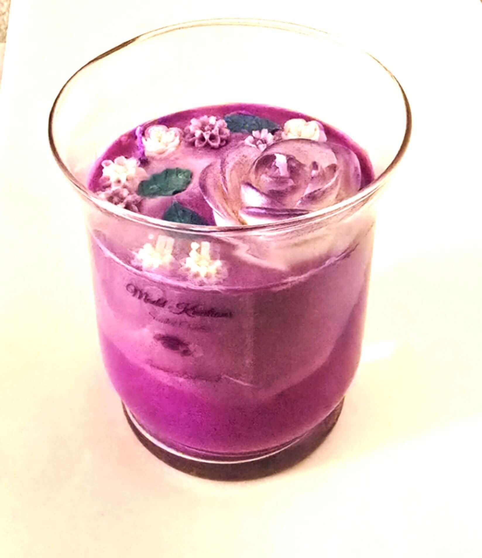 Lavender Valley Luxury Candle in a glass jar, featuring purple hues and decorative flowers on top.